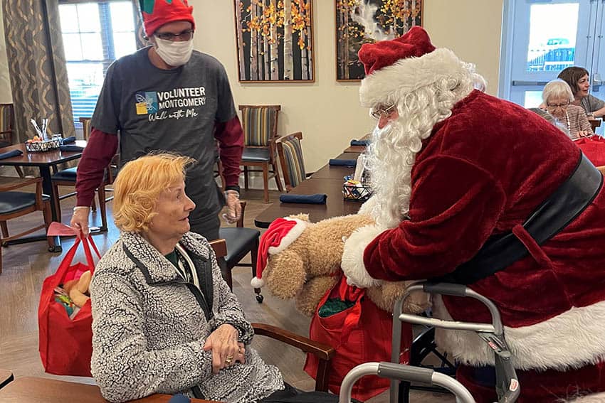 Robbie Hall and Santa handing a bag to a resident of English Meadows